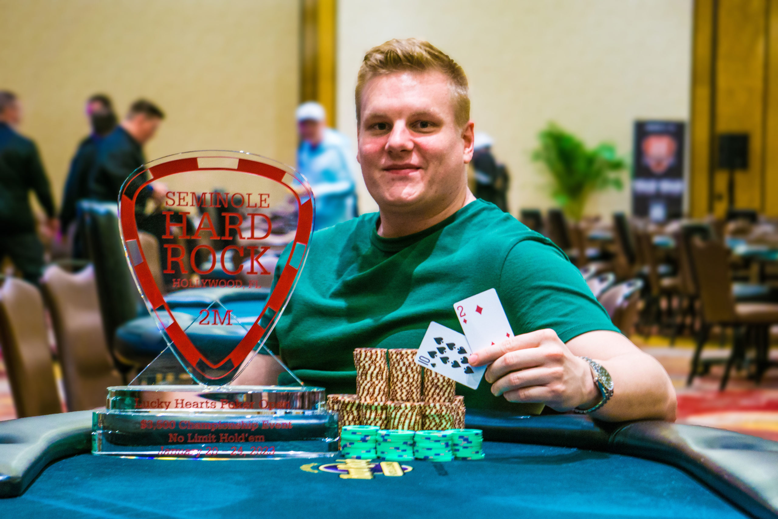 Lucky Hearts Poker Open Champion Marius Gierse poses with a pile of chips, the Championship trophy, and he's holding two cards -- 10-2 offsuit.
